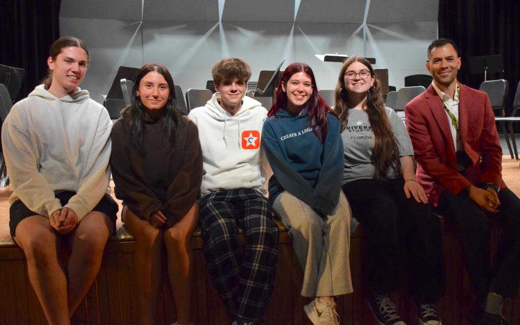 six people sitting onstage